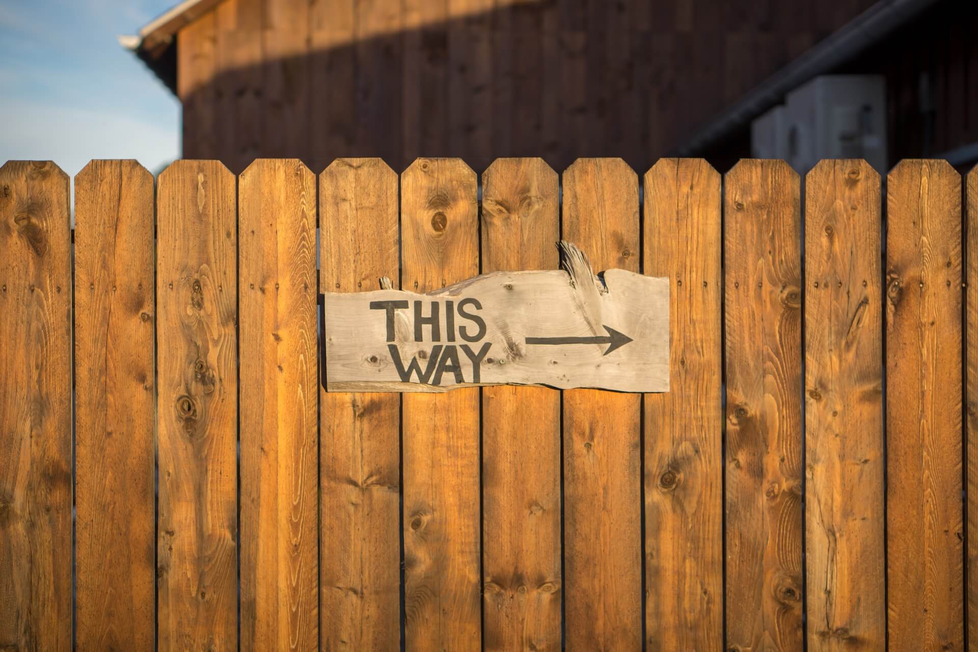 Fence with a 'this way' sign